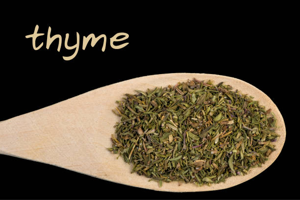 istock thyme on wooden spoon isolated on black background 1128459853