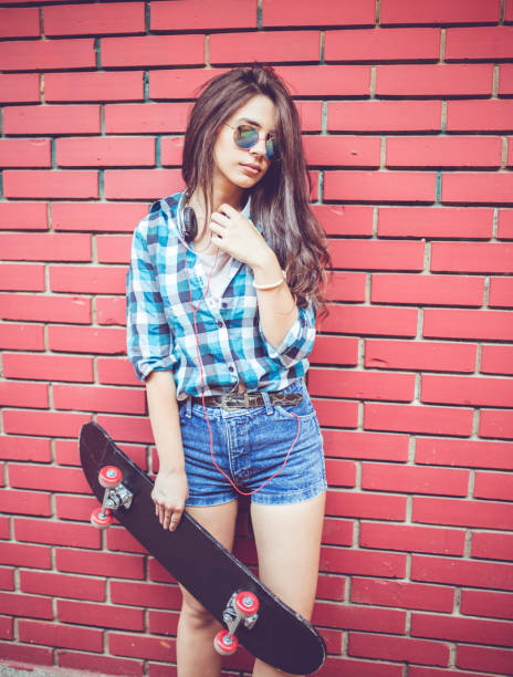 istock Girl by red brick wall with skateboard 1128461407