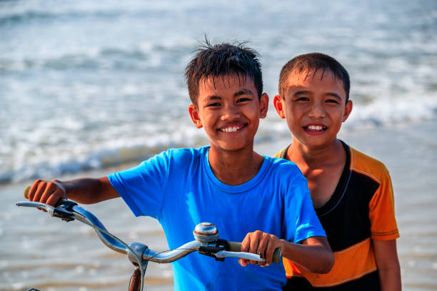 Vietnamese young boys riding a bicycle on the beach, Vietnam
