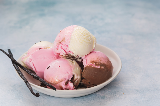 Bowl of Neapolitan ice cream scoops on rustic background. Selective focus, copy space