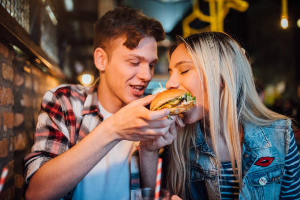 istock Woman taking a bite of man's hamburger 1128481005