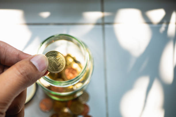 Hand grab coins from glass jar.