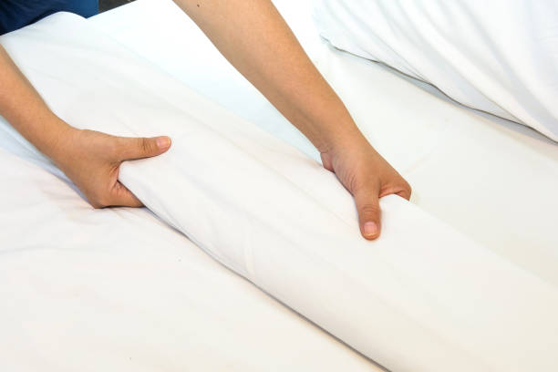 istock Hand set up white bed sheet in bedroom 1128482025