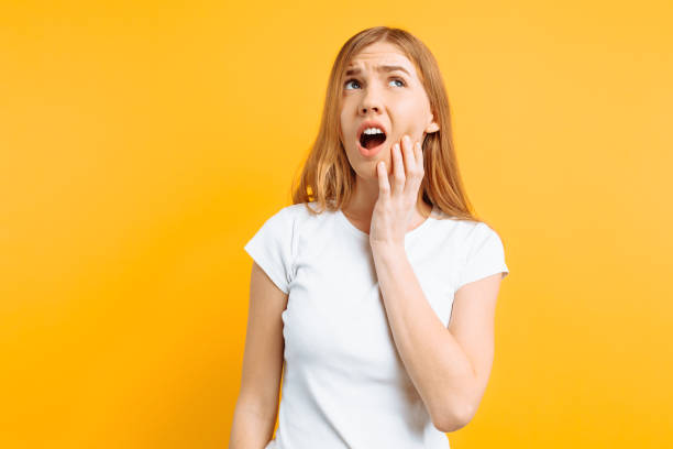 istock Young sad girl is having a toothache, on yellow background 1128482290