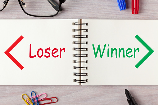 Loser versus Winner words written on open spiral notebook and various stationery. Business Concept