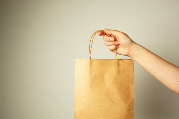 開催クラフト紙パッケージ、デザインのモック女性の手のクローズ アップ。ゼロの子供の概念。 - paper bag bag brown handle ストックフォトと画像