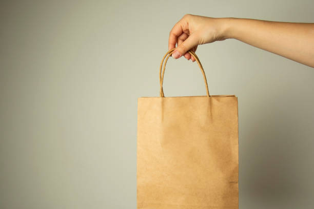 istock Closeup of female hand holding craft paper package., design mock up. Zero easte concept. 1128492035