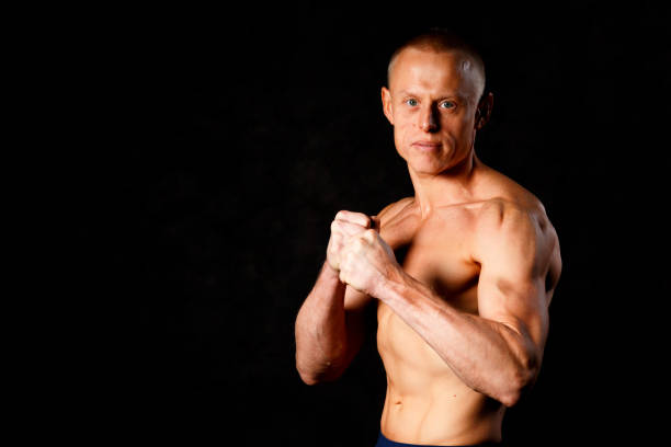 musculaire jeune homme en studio sur fond foncé montre les différents mouvements et les parties du corps - male torso abdominal muscle the human body photos et images de collection