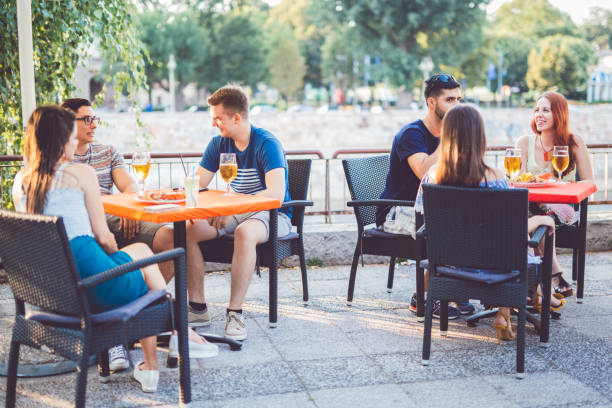 Young people relaxing in patio section Young people relaxing in the patio section of a pub over a cold drink and a tasty snack bar exterior stock pictures, royalty-free photos & images