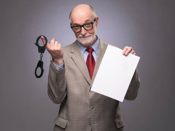 istock Senior man with handcuffs and paper 1128503907