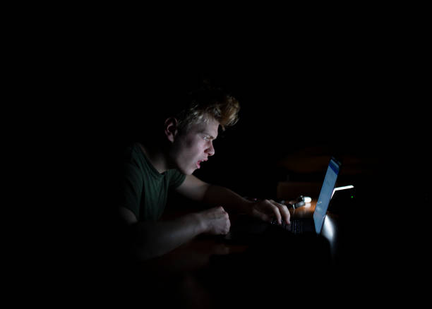 istock Man works at a laptop at night 1128508902