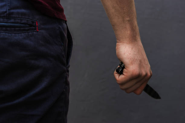 istock Young guy with a knife about to attack, over dark background. 1128509709