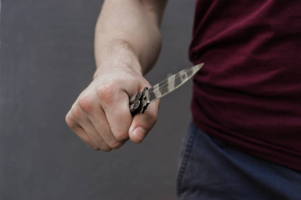istock Young guy with a knife about to attack, over dark background. 1128509750