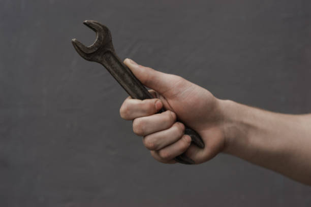 istock Man holding wrench on a dark background. 1128509842