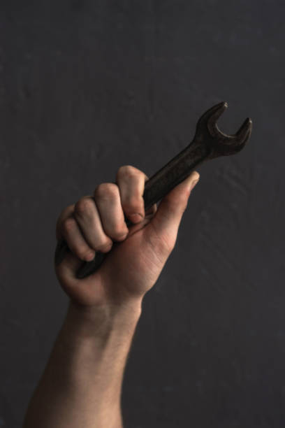 istock Man holding wrench on a dark background. 1128509851