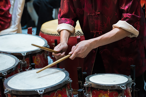 An adult drummer having drums performance in the Chinese Orchestra band during Chinese new year.