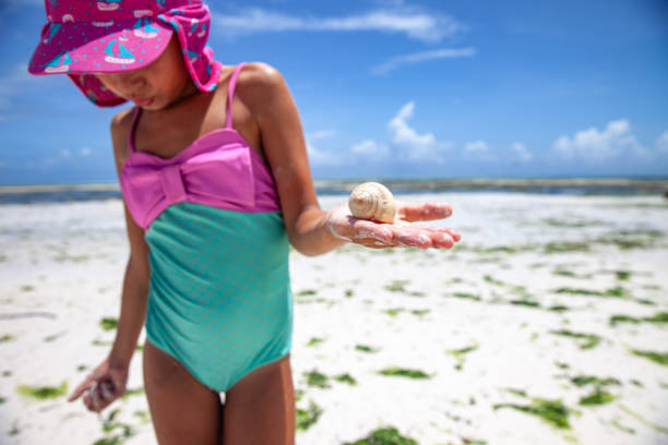 istock Young Girl Searching Sea Shells on Beach 1128511389