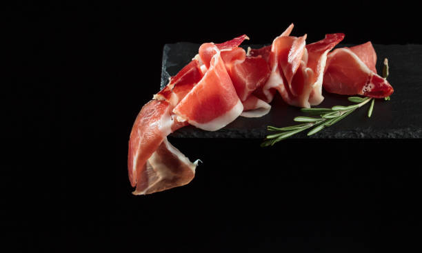 istock Prosciutto with rosemary on a black background. 1128513986