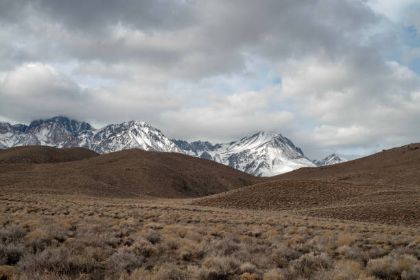 istock brown winter desert valley, hills, snowy mountain peaks 1128514021