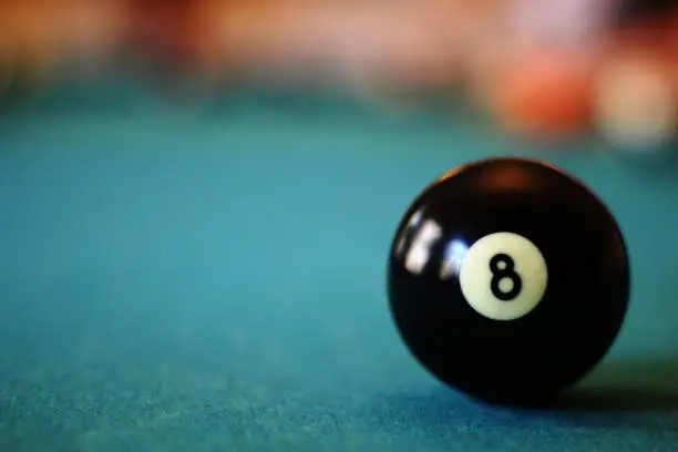 Eight ball on pool table with copy space on the right (concept - behind the eight ball)