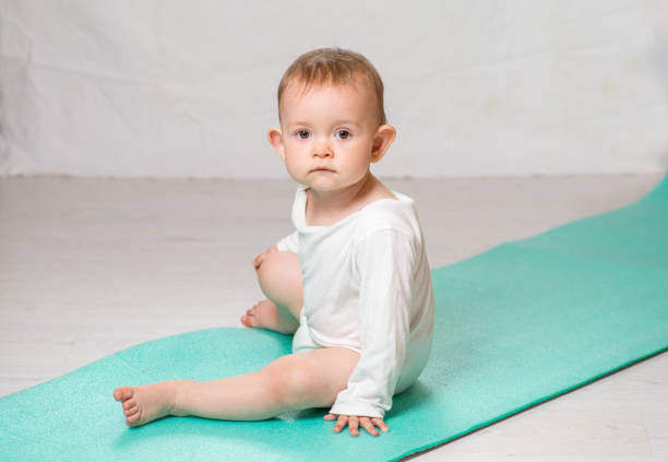 dziecko wykonuje ćwiczenia fizyczne na macie do jogi. joga dla niemowląt - male body sport exercising zdjęcia i obrazy z banku zdjęć