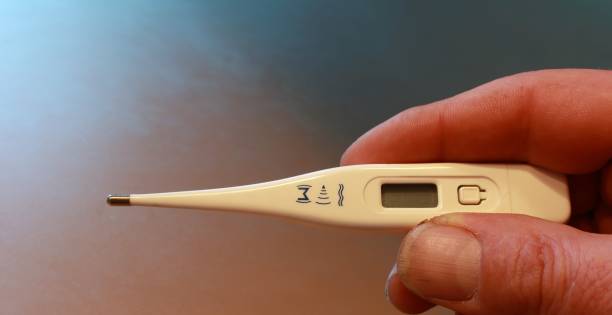 fever Man holds a fever thermometer in his hand temperatur stock pictures, royalty-free photos & images