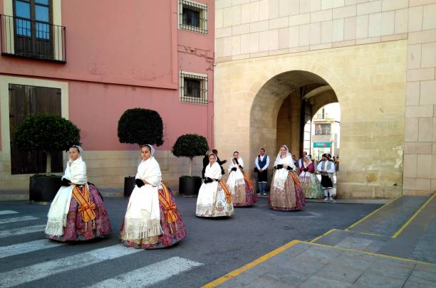 un desfile en una fila de mujeres vestidas whith tradicionales coloridas ropas y vestidos cerca del ayuntamiento de elche - elche españa fotografías e imágenes de stock