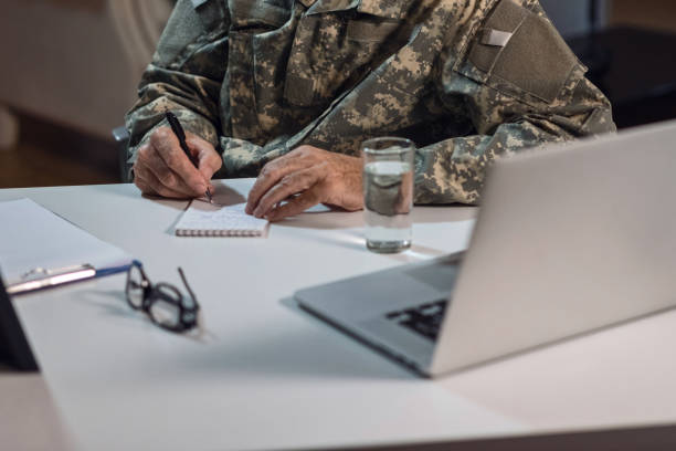 istock Unrecognizable mature soldier taking notes on the paper. 1128522890