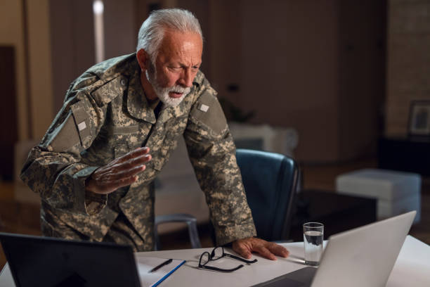istock Displeased mature sergeant reading an e-mail on laptop in the office. 1128523884