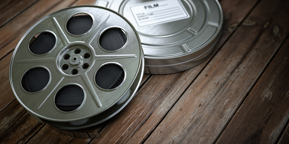 Vintage film reel with filmstrip on wood background. Video, cinema, multimedia concept. 3d illustration