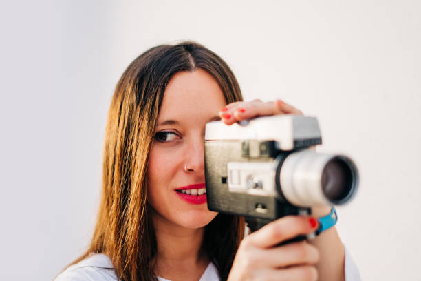 istock young smiling woman with red lips using a retro video camera isolated on a white background 1128525567