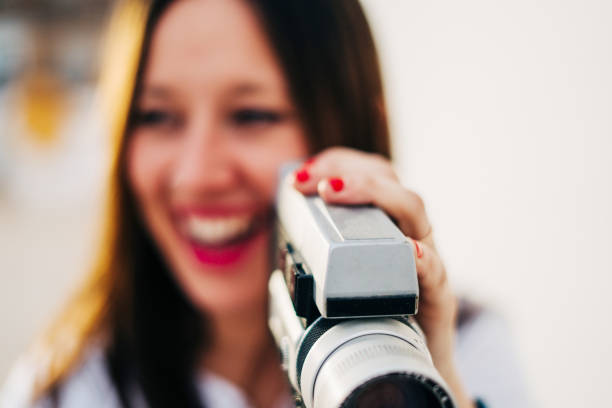 istock young smiling woman with red lips using a retro video camera isolated on a white background 1128525588