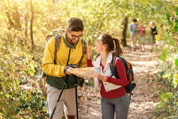 istock Cheerful hikers looking at map and looking for right way. Autumn time in forest exterior. 1128529093