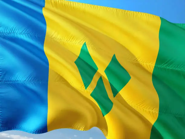 Flag of Saint Vincent And The Grenadines waving in the wind against deep blue sky. High quality fabric.