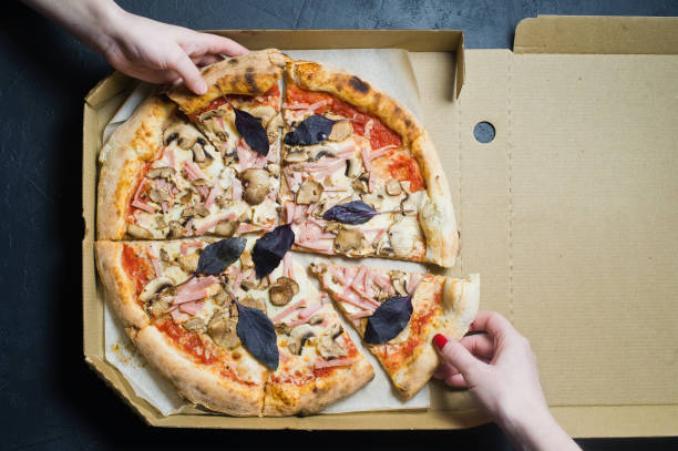 istock Two hands take a piece of freshly baked Italian pizza. 1128541864