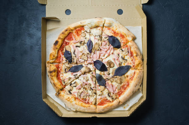 istock Pizza in a cardboard box, dark background. 1128541901