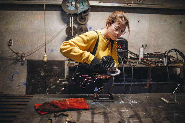 Young and confident metal working girl Young girl working at a metal workshop, grinding metal with grinder. metal worker stock pictures, royalty-free photos & images