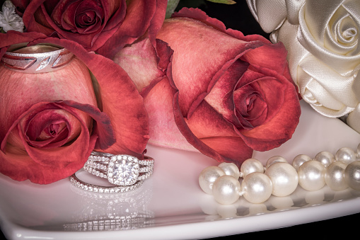Roses on White Plate with Wedding Rings, Pearls & Bouquet