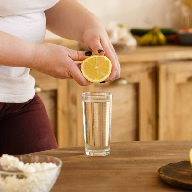 istock overweight woman squeezing lemon juice into water 1128548917