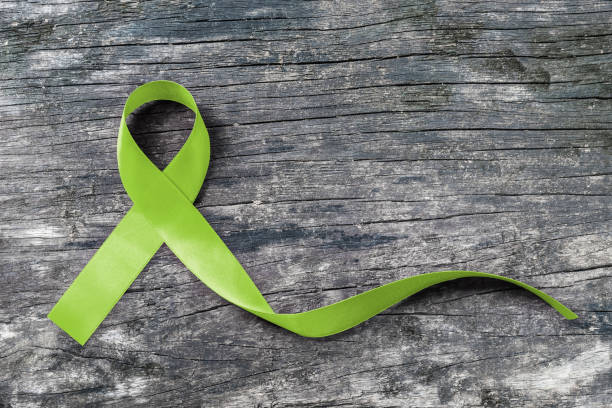 Lime Green ribbon for Lymphoma Cancer and mental health awareness for supporting and helping patient with illness (bow isolated with clipping path on aged wood) Lime Green ribbon for Lymphoma Cancer and mental health awareness for supporting and helping patient with illness (bow isolated with clipping path on aged wood) lymphoma photos stock pictures, royalty-free photos & images