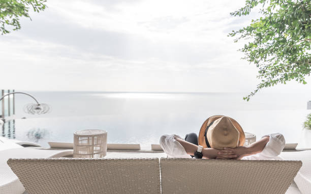 vacaciones de relajación del empresario tome fácil feliz descansando en la silla de playa con piscina junto a la piscina frente a la playa resort hotel con mar u océano vista verano soleado cielo y al aire libre - pasajero fotos fotografías e imágenes de stock