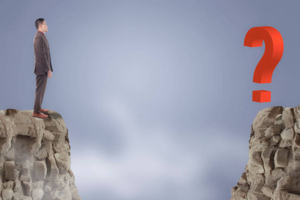 Personal development concept. Future success with risky challenge concept, portrait of Asian businessman standing at the edge of cliff, facing question mark across the gap