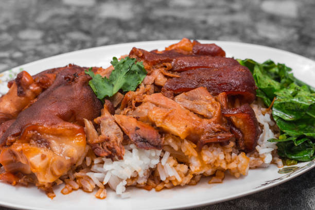 istock German pork knuckle with rice, vegetable and fruit served with sauce on wooden table. 1128572229