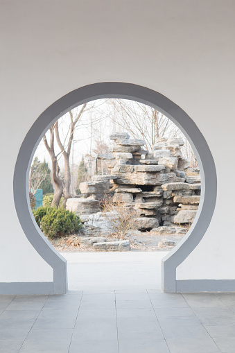 A Moon Gate is a circular opening in a garden wall that acts as a pedestrian passageway, and a traditional architectural element in Chinese gardens.