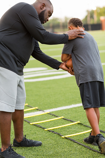 American Football coach teaching and training a young athlete.