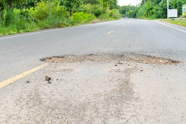 istock dangerous  hole in the asphalt road 1128607864