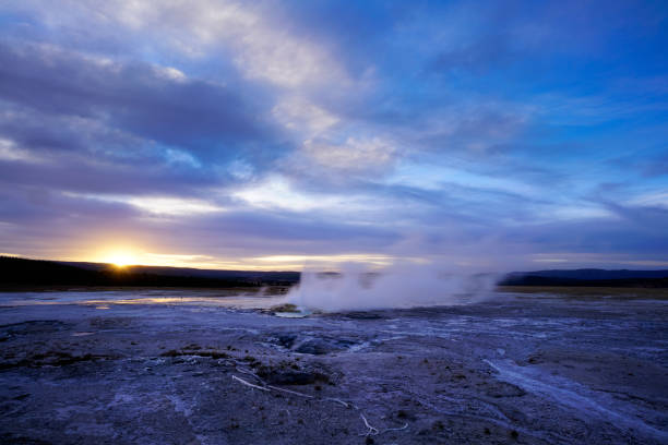 Old faithful geyser eruption at sunny blue sky, Yellowstone National Park, USA.