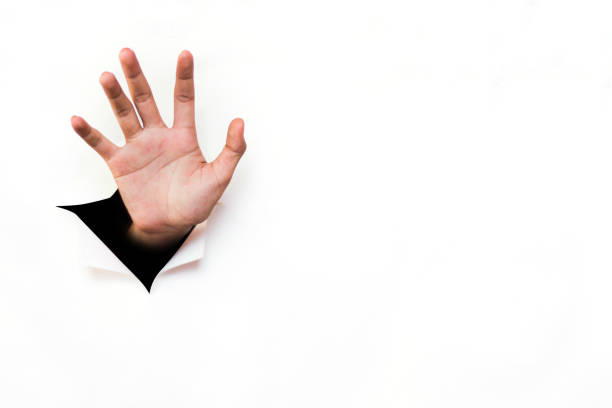 istock Hand reaching out from torn white paper sheet 1128617016