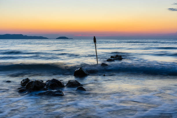 istock Stones in ocean water in orange sky twilight atmosphere 1128619367