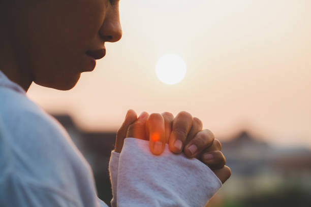 mujer orando en la mañana en el fondo del amanecer. concepto de cristianismo. orar el fondo. concepto de amor de esperanza de fe. - female meditating human hand christianity fotografías e imágenes de stock